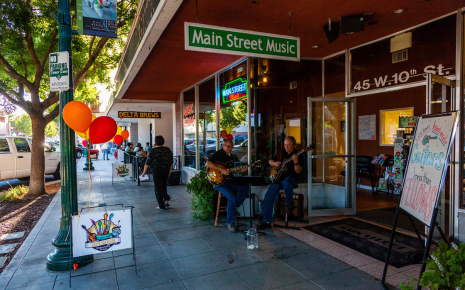 Musicians perform outside Main Street Music in downtown Tracy as pedestrians walk along the sidewalk.